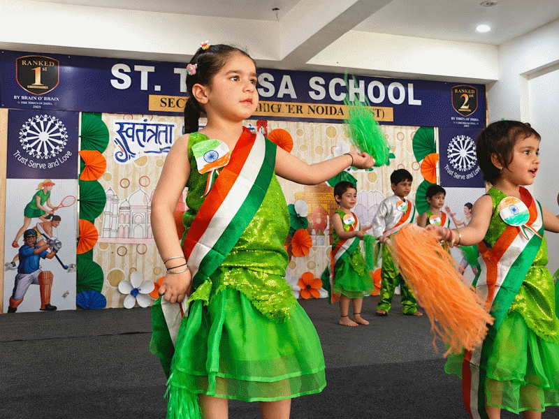 Children in green dresses performing on stage at St. Teresa School